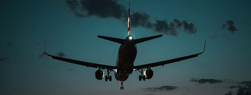 Passenger-Airplane-Approaching-Landing-With-Gear-Down-at-Dusk Passenger airplane descending toward an airport with its landing gear extended against the fading evening sky