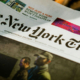 Person reading a printed edition of The New York Times newspaper, reflecting traditional journalism and the experience of following current events