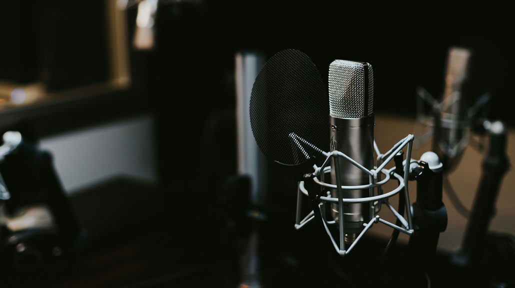 Professional-Studio-Microphone-in-Music-Recording-Room Professional studio microphone positioned inside a music recording room, representing sound production, musical creativity, and audio recording
