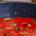 Rich red tomato sauce topped with fresh green herbs in a cooking pan, showing the color and texture of the prepared sauce
