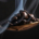 Spoon filled with roasted coffee beans surrounded by delicate wisps of white smoke or steam rising from the beans