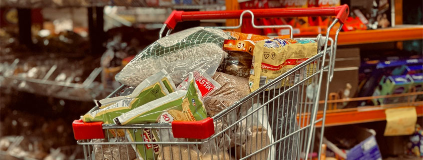 Shopping cart filled with groceries and everyday food products during a supermarket shopping trip
