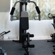 Compact home gym featuring an exercise machine and workout weights arranged in a small indoor fitness space