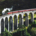 Steam train crossing the historic Glenfinnan Viaduct surrounded by the mountainous landscape of the Scottish Highlands