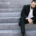 Upset young businessman sitting alone on outdoor stairs, appearing stressed and overwhelmed by work-related problems