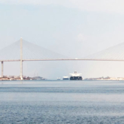 Cargo ship approaching the Suez Canal suspension bridge in Egypt, with the vessel visible in the distance along the waterway