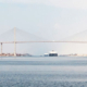 Cargo ship approaching the Suez Canal suspension bridge in Egypt, with the vessel visible in the distance along the waterway