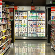 Supermarket aisle displaying a variety of food products including cheese, dairy items, candy, cookies, and biscuits