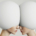 Surreal artwork depicting two human faces with eggshell-shaped heads pressed together forehead to forehead, with only their noses, mouths, and chins visible