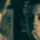 Teenager holding a cigarette to his mouth with two fingers while looking at his reflection in a mirror, with his back visible in the foreground