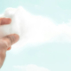 Human hand reaching into the sky and grasping the edge of a white cloud in a surreal creative composition