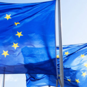 Three European Union flags displaying a circle of twelve yellow stars against a blue background