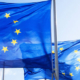 Three European Union flags displaying a circle of twelve yellow stars against a blue background