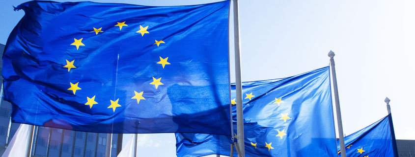 Three European Union flags displaying a circle of twelve yellow stars against a blue background