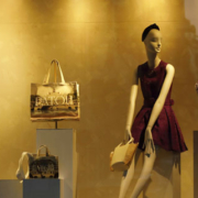 Three mannequins wearing different fashionable outfits and dresses, arranged in standing and seated positions