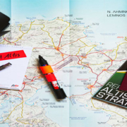 Travel essentials including a map, compass, passport, camera, notepad, and marker arranged together for navigation and trip planning