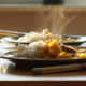 Two plates of freshly served hot food on a table with visible steam rising from the meals