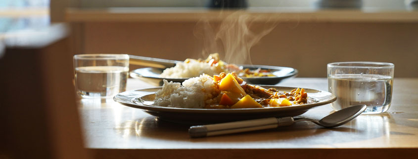 Two-Plates-of-Hot-Food-With-Rising-Steam-on-Table Two plates of freshly served hot food on a table with visible steam rising from the meals