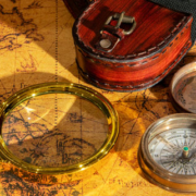Vintage geographical map with an antique compass and handheld magnifying glass for examining locations and routes