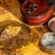 Vintage geographical map with an antique compass and handheld magnifying glass for examining locations and routes