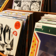 Rows of music albums with colorful covers arranged in wooden display bins along an aisle inside a record store