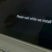 Windows laptop or tablet displaying the Windows logo and a message asking users to wait while a system update installs