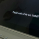 Windows laptop or tablet displaying the Windows logo and a message asking users to wait while a system update installs