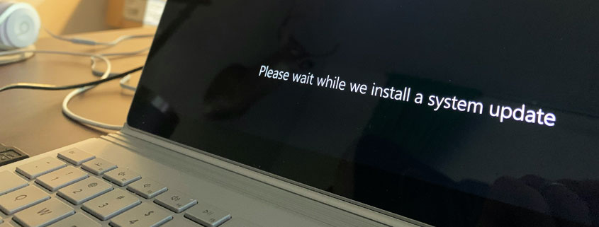 Windows-Device-Displaying-System-Update-Installation-Screen Windows laptop or tablet displaying the Windows logo and a message asking users to wait while a system update installs