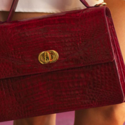 Fashion handbag hanging beside a woman's legs, with the lower portion of her skirt visible as she stands