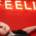 Woman lying comfortably on a sofa with her eyes open and one hand visible beneath a sign displaying the word Feelings