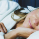 Woman wearing a white robe lying comfortably on a bed while resting