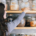 Woman with long hair reaching for a labeled glass jar among shelves filled with neatly organized dry foods and pantry ingredients