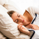 Woman lying in bed with her eyes closed, appearing to sleep peacefully