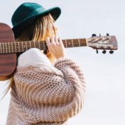Woman-Walking-With-Guitar-on-Shoulder-and-Green-Hat.jpg