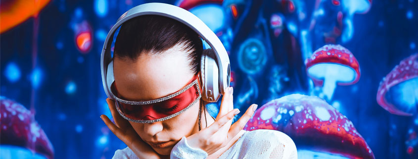 Woman-Wearing-Futuristic-Cyber-Glasses-and-Headphones-Listening-to-Music Woman wearing futuristic wraparound cyber glasses and headphones, holding both sides of her headphones while looking downward and concentrating on music