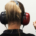 Woman viewed from behind wearing headphones and raising her index finger to indicate hearing a sound during a hearing test