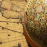 Globe representing planet Earth positioned on top of a geographic world map, illustrating different perspectives of global geography
