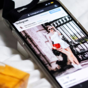 iPhone resting beside elegant earrings, a perfume bottle, and a black Chanel-branded lanyard arranged on a bed